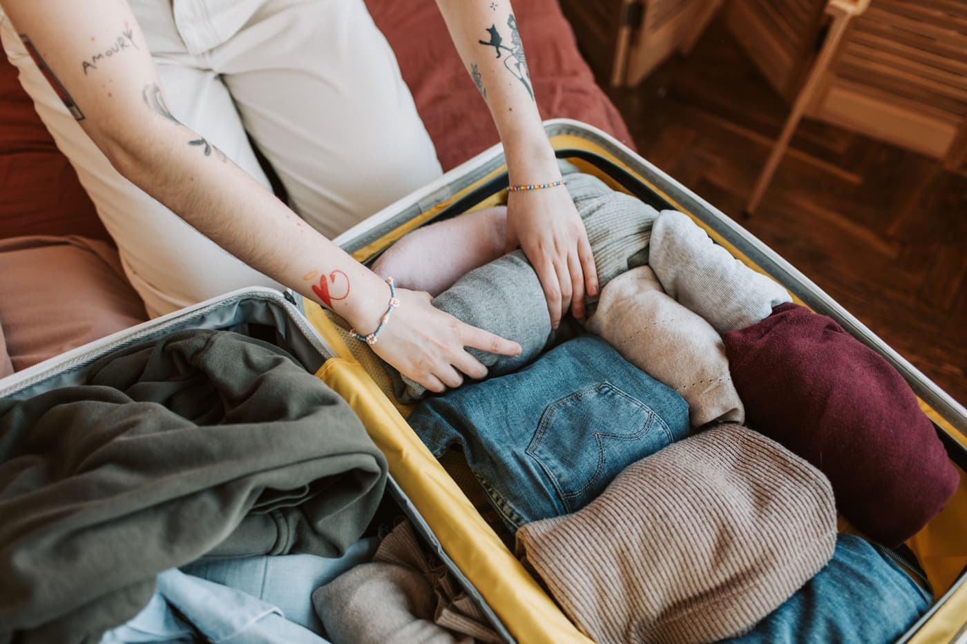 A traveler folding and packing clothes into a suitcase